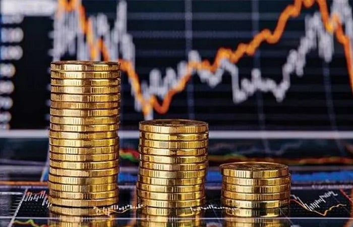 صفوف من العملات الذهبية أمام شاشة مؤشرات تداول