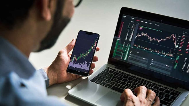 شخص يتداول باستخدام لاب توب وموبايل