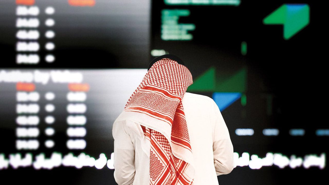 رجل يقف امام شاشة تداول 